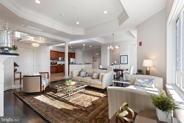 living room with crown molding, a raised ceiling, dark wood-type flooring, and a chandelier