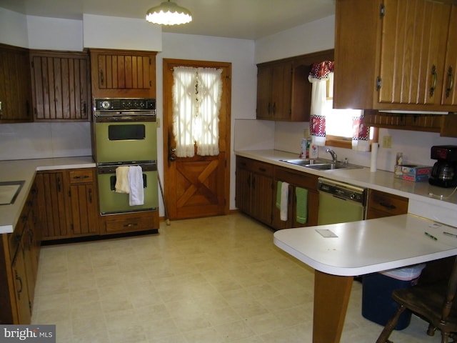 kitchen featuring sink, a kitchen breakfast bar, stainless steel dishwasher, double oven, and kitchen peninsula