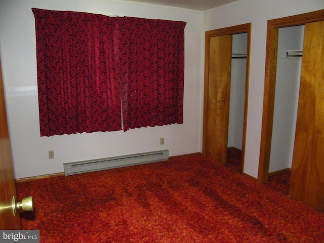 unfurnished bedroom with multiple closets and a baseboard heating unit