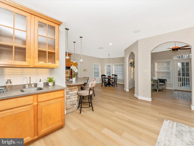 kitchen with hanging light fixtures, light hardwood / wood-style flooring, ceiling fan, and sink