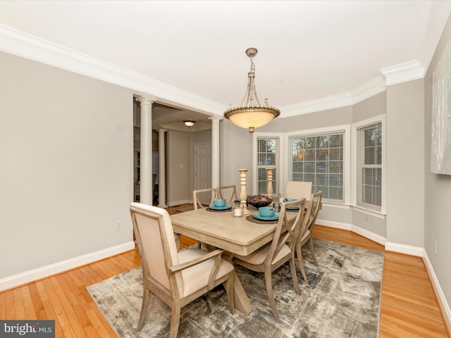 dining space with wood-type flooring, ornate columns, and crown molding