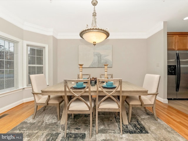 dining space with hardwood / wood-style floors and crown molding