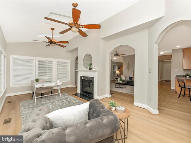 living room featuring a fireplace, high vaulted ceiling, and light hardwood / wood-style flooring