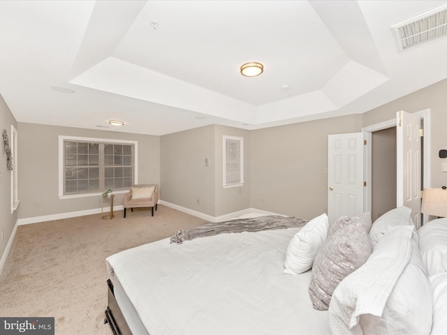 bedroom featuring light carpet and a tray ceiling