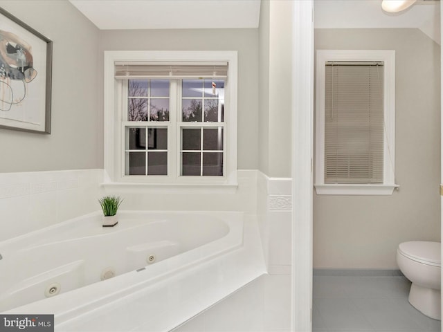 bathroom with a washtub, tile patterned flooring, and toilet