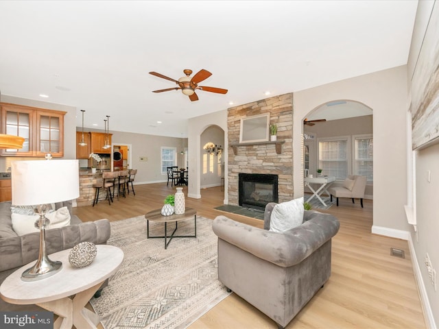 living room with ceiling fan, a fireplace, and light hardwood / wood-style floors