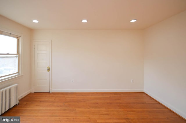 spare room featuring radiator and light hardwood / wood-style flooring