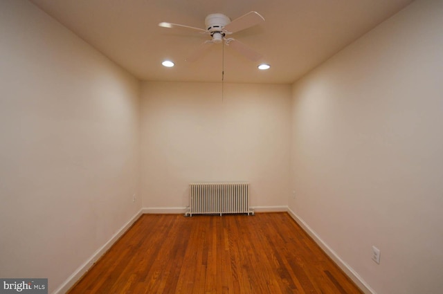 unfurnished room featuring ceiling fan, radiator heating unit, and wood-type flooring