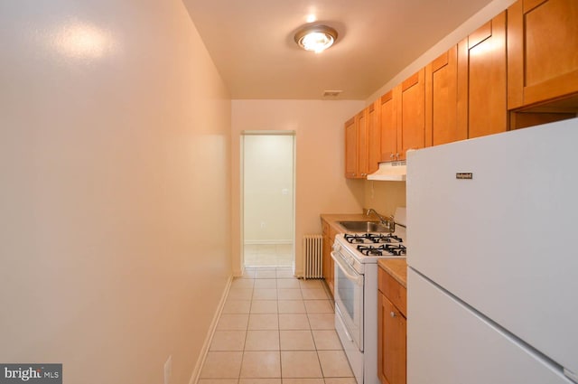 kitchen with sink, white appliances, radiator, and light tile patterned flooring