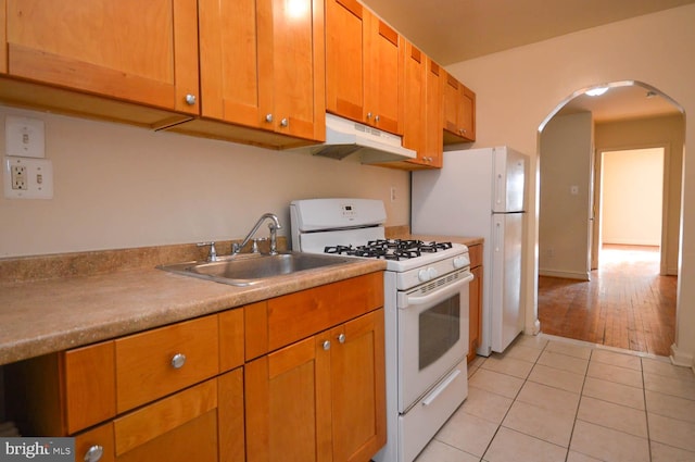 kitchen with white gas stove, light wood-type flooring, and sink