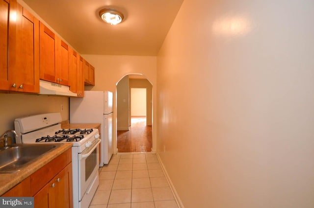 kitchen with light tile patterned floors, white appliances, and sink