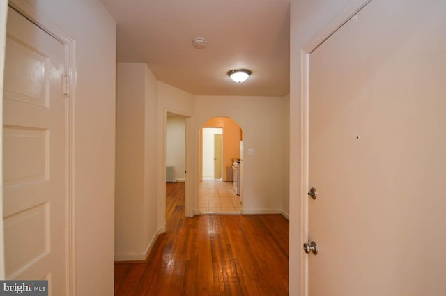 corridor with wood-type flooring and independent washer and dryer