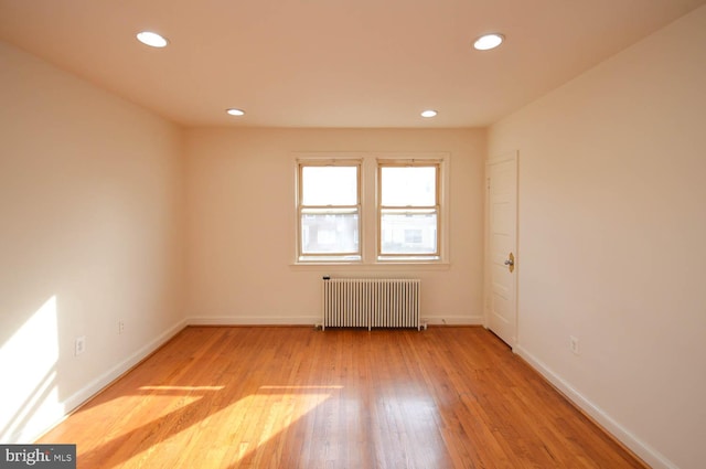 unfurnished room with light hardwood / wood-style flooring and radiator