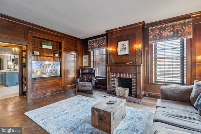 living room with crown molding, built in features, wooden walls, and a brick fireplace