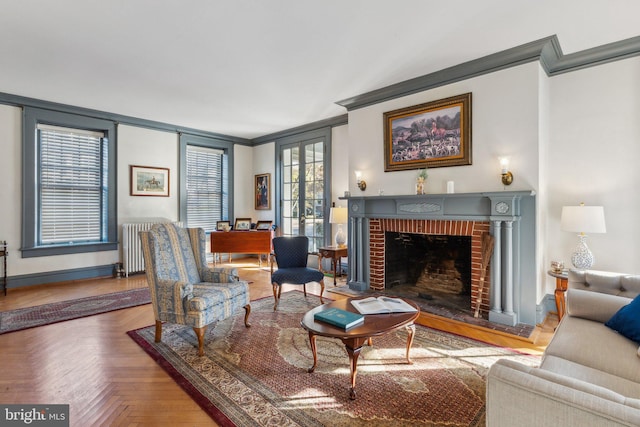 living area with radiator heating unit, a brick fireplace, parquet floors, and crown molding