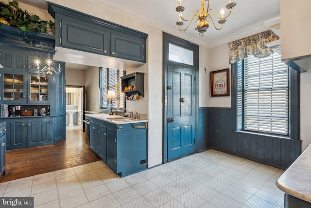 kitchen with pendant lighting, sink, light wood-type flooring, ornamental molding, and blue cabinetry