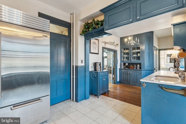 kitchen featuring built in refrigerator, sink, light wood-type flooring, and blue cabinets