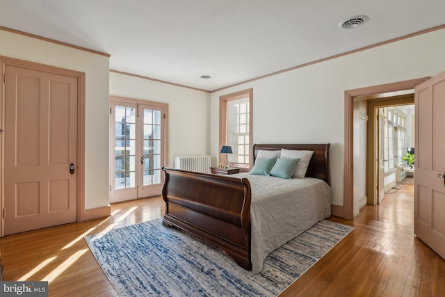 bedroom featuring access to outside, light hardwood / wood-style flooring, french doors, and ornamental molding