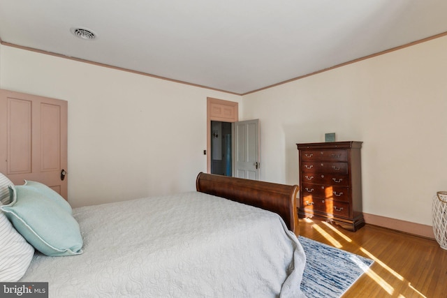 bedroom with wood-type flooring and ornamental molding