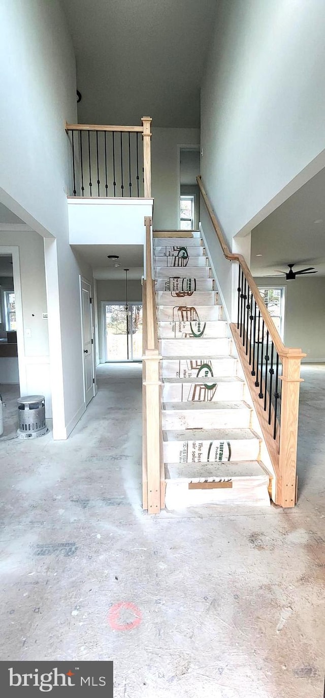 stairway with ceiling fan and concrete floors