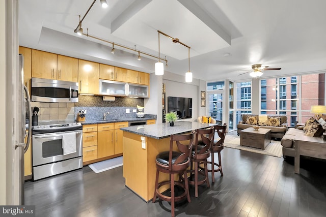 kitchen featuring sink, a center island, hanging light fixtures, dark hardwood / wood-style flooring, and appliances with stainless steel finishes