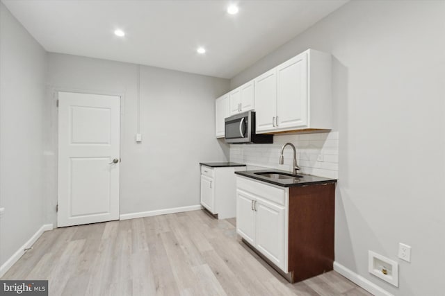 kitchen featuring backsplash, sink, white cabinets, and light hardwood / wood-style floors