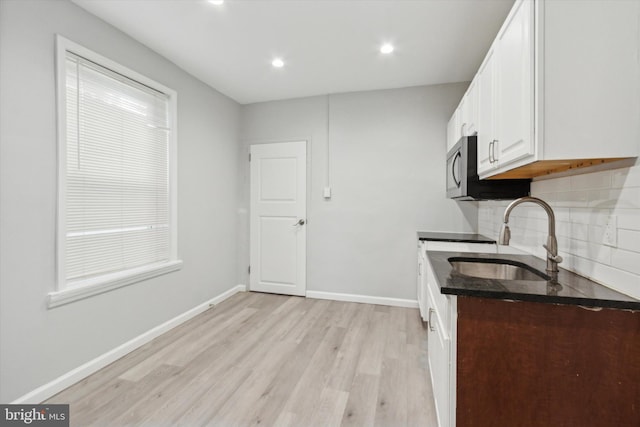 kitchen with decorative backsplash, sink, white cabinets, and light hardwood / wood-style floors