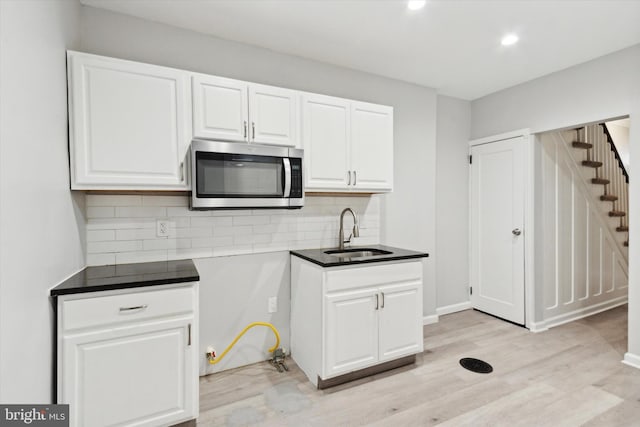 kitchen with backsplash, light hardwood / wood-style floors, white cabinets, and sink