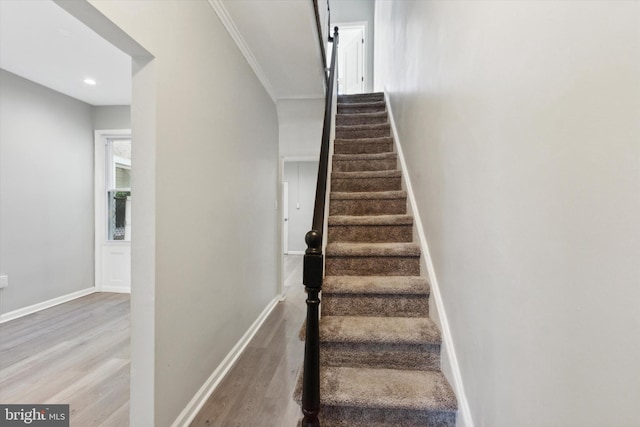 stairs with hardwood / wood-style floors and crown molding