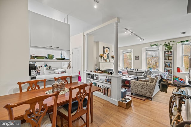 dining room with ornate columns, light wood-type flooring, and track lighting