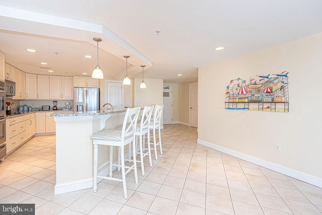 kitchen with light stone counters, an island with sink, stainless steel appliances, and light tile patterned floors