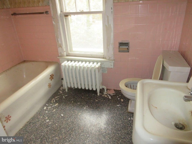 bathroom featuring toilet, radiator heating unit, tile walls, a bath, and sink