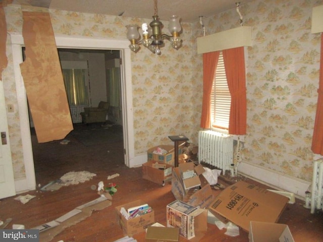 unfurnished dining area with wood-type flooring, a notable chandelier, and radiator heating unit