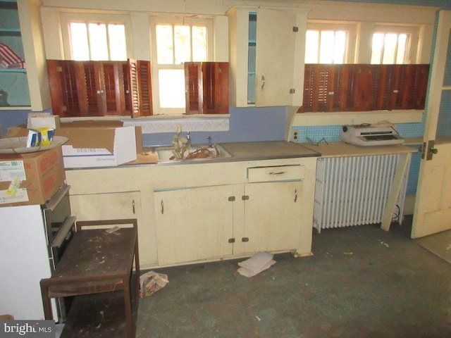 kitchen with radiator, white cabinetry, plenty of natural light, and sink