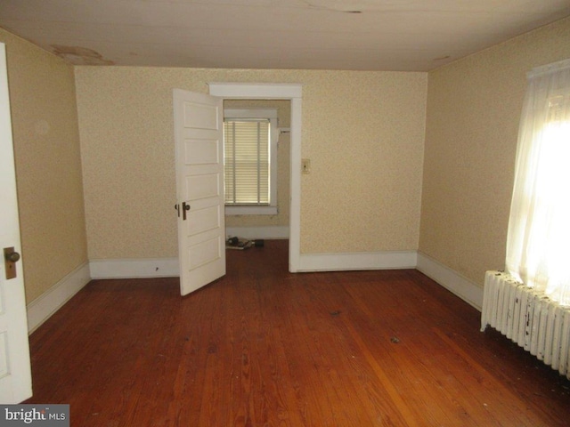 unfurnished room with dark hardwood / wood-style floors and radiator heating unit