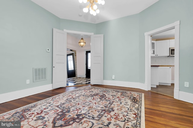 unfurnished room featuring dark hardwood / wood-style flooring and a notable chandelier