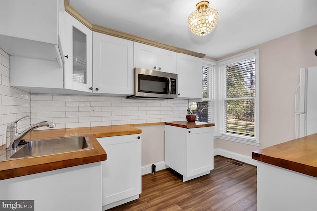 kitchen with decorative backsplash, dark hardwood / wood-style flooring, sink, butcher block countertops, and white cabinetry