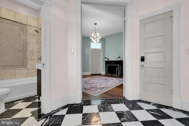 bathroom featuring toilet, hardwood / wood-style flooring, an inviting chandelier, and tiled shower / bath