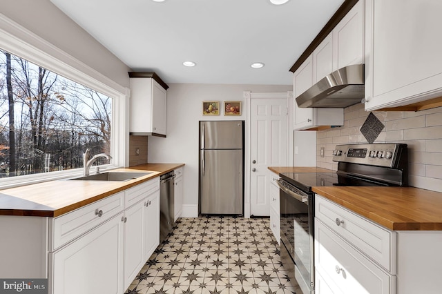 kitchen featuring wood counters, appliances with stainless steel finishes, extractor fan, and sink