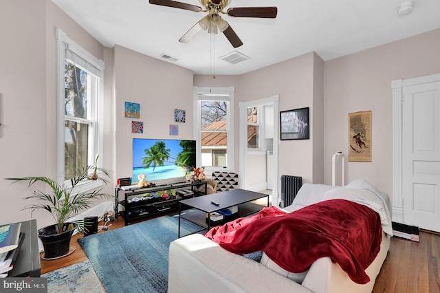 living room with radiator, a wealth of natural light, ceiling fan, and dark wood-type flooring