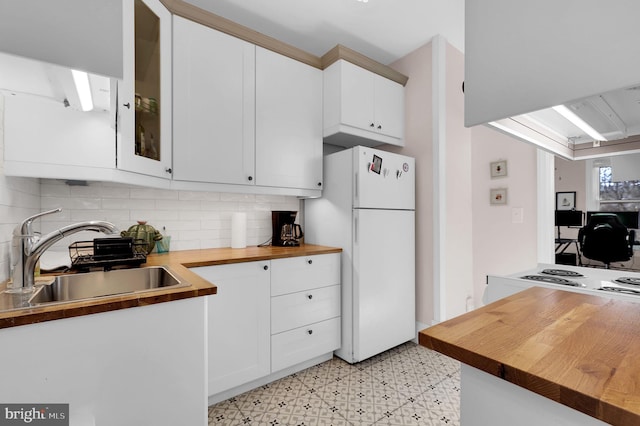 kitchen with wood counters, white cabinets, sink, decorative backsplash, and white fridge