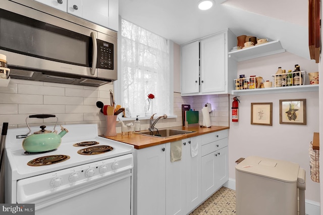 kitchen with wood counters, backsplash, white range with electric cooktop, sink, and white cabinetry