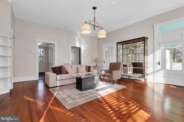 living room with dark wood-type flooring and an inviting chandelier