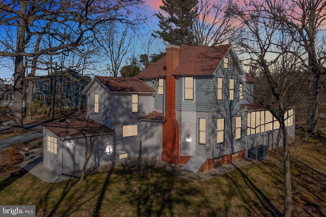 property exterior at dusk with a lawn and central air condition unit