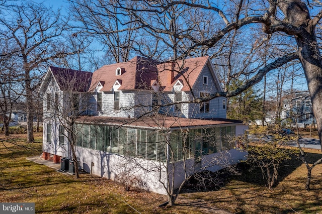 view of side of home with a lawn, a sunroom, and central AC unit