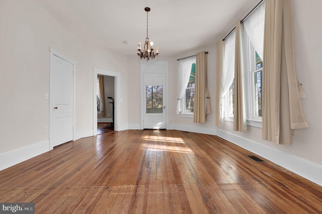 empty room with hardwood / wood-style floors and a notable chandelier