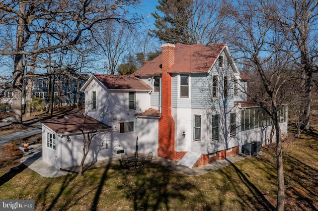 view of side of home featuring a yard, central AC, and a sunroom