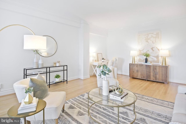 living area with baseboards, ornamental molding, and wood finished floors