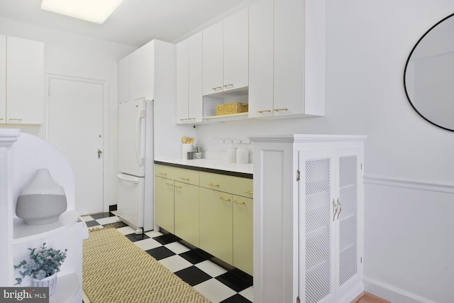 kitchen with light floors, open shelves, light countertops, freestanding refrigerator, and white cabinetry