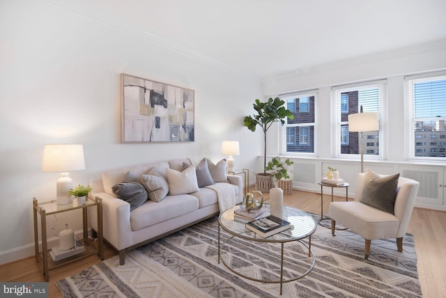 living room with light wood-type flooring, visible vents, baseboards, and crown molding